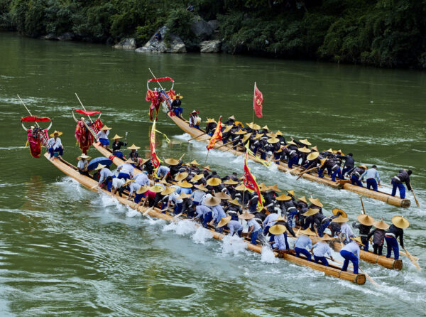 Nachdem das Drachenboot zu Wasser gelassen wurde, besprenkelt der Zauberer, der das Ba Mao-Gras hält, das Fluss­wasser und ruft: „Väter und Brüder, arbeitet zusammen, um das Drachenboot zu pad­deln, habt den Mut, um den ersten Platz zu kämpfen!“ Das Drachenbootrennen der Hmong wird von einem Trommler an­ge­führt, der die Ruderer im Gleichklang paddeln lässt. Bild aus der Story: „Die Legende vom Qingshui Fluss“ (China), Foto und Bericht: Huimin Kuang